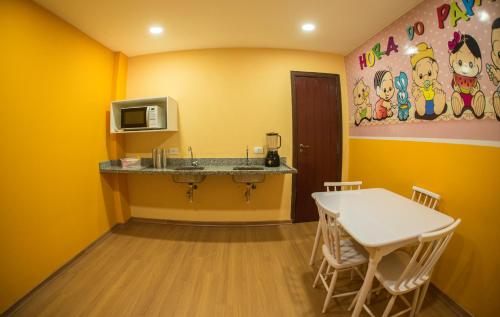 a yellow room with a table and a microwave at Hotel Matsubara in Campos do Jordão