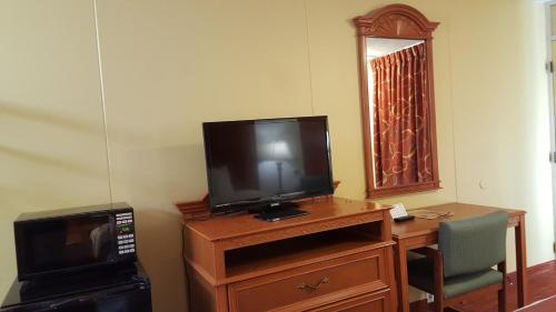 a television on a wooden dresser with a microwave at Plaza Inn Springfield in Springfield
