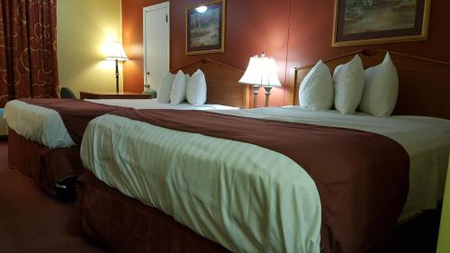 a hotel room with two beds with white pillows at Plaza Inn Springfield in Springfield