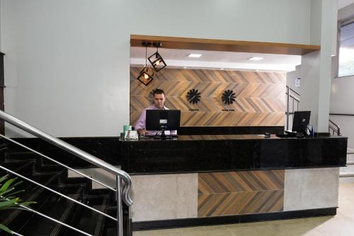 a man sitting at a counter with a laptop at Hotel Plaza Cascavel in Cascavel