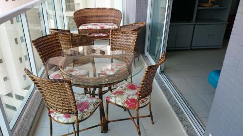 a group of chairs and a glass table on a balcony at Studio mobiliado in Santos