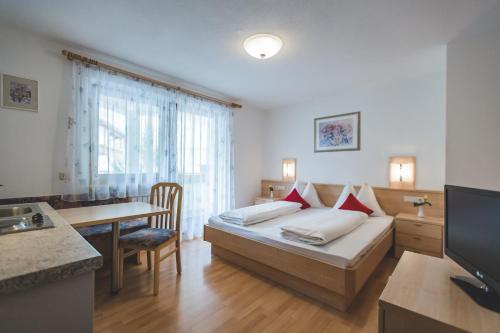 a hotel room with a bed and a table at Garni Appartement Alpenresidence in Cadipietra