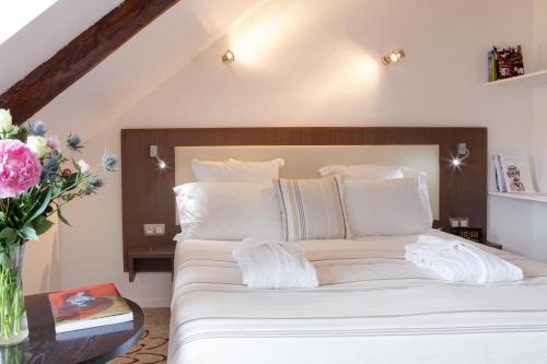 a bedroom with a bed with white sheets and a vase of flowers at Hôtel Le Benhuyc in Binic-Etables-sur-Mer