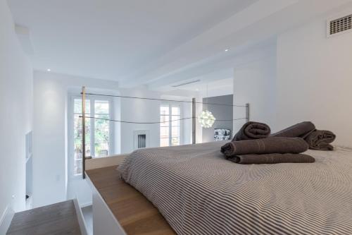 une chambre blanche avec un lit avec deux oreillers marron dans l'établissement Magnificent Loft - very central, à Nice