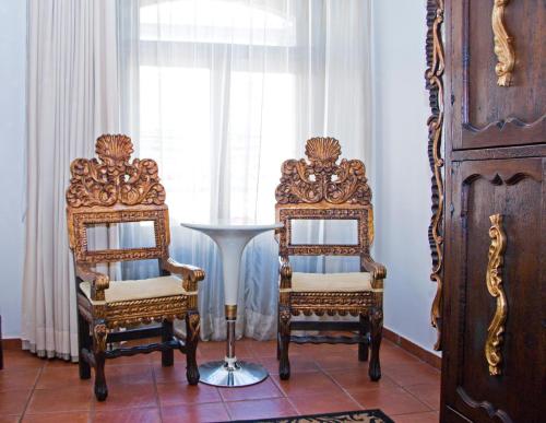 two chairs and a table in a room with a window at Hotel Herencia By Hosting House in Morelia