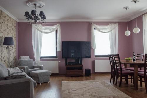 ヴィスワにあるApartament Premium Deluxのピンクの壁のリビングルーム(テーブル、椅子付)