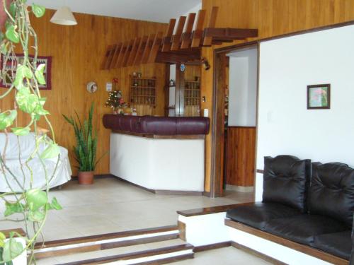 a living room with a black leather couch in a room at Amanitas Hotel in Villa Carlos Paz
