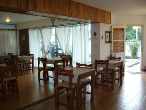 a dining room with tables and chairs and windows at Amanitas Hotel in Villa Carlos Paz