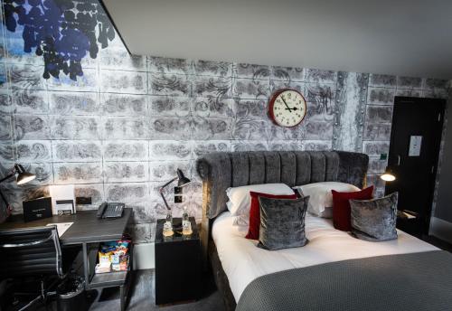 a bedroom with a bed and a desk and a clock at Malmaison Oxford in Oxford