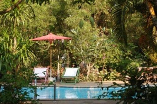 a pool with a red umbrella and two chairs and a table at Mairood Resort in Ban Mai Rut