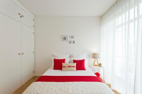 a bedroom with a large bed with red pillows at Sereia Garden Apartment in Coimbra