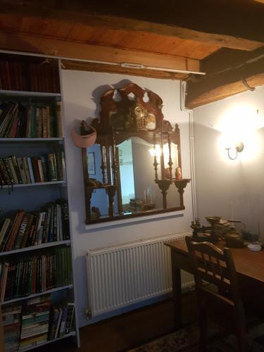 a dining room with a mirror and a table and books at Le Vieux Couvent in Deviat