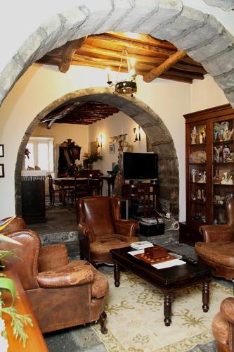 a living room with leather furniture and a stone fireplace at Ponta Delgada - Casa Rural in Ponta Delgada