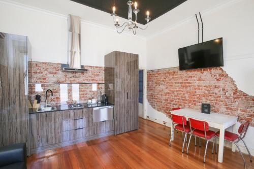 a kitchen with a white table and a brick wall at Indulge Apartments - The Urban Collection in Mildura