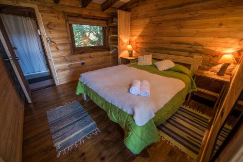 una camera con un letto in una baita di tronchi di Onai Hostel a Las Trancas
