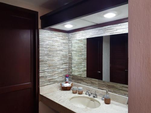 Un baño con lavabo y un espejo grande. en Suite frente al Mar, en Cancún