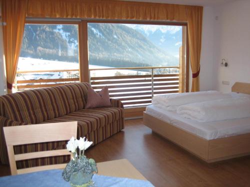 sala de estar con sofá, cama y ventana en Garni - Appartement Neumairhof, en Rasun di Sopra