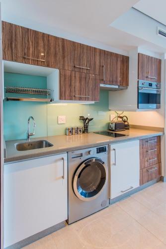a kitchen with a washing machine and a sink at The Capital Pearls Hotel in Durban