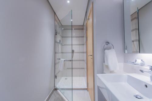 a bathroom with a glass shower and a sink at The Capital Pearls Hotel in Durban