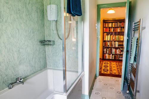 a bathroom with a bath tub and a book shelf at Shelburne Lodge in Cairnbaan