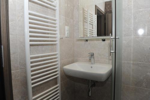 a white bathroom with a sink and a mirror at Penzion Panorama in Liptovský Mikuláš