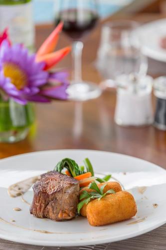 a plate with a steak and vegetables on a table at Ramada Resort by Wyndham Port Vila in Port Vila