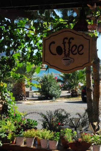 a sign for a coffee shop with potted plants at Aliye Hanim Hotel in Ayvalık