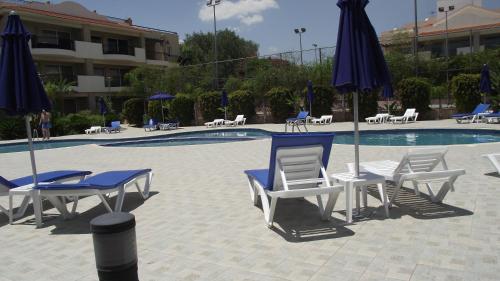 a group of chairs and umbrellas next to a pool at Pyla Gardens A101 in Pyla
