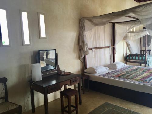 a bedroom with a bed and a desk with a mirror at Subira House in Lamu