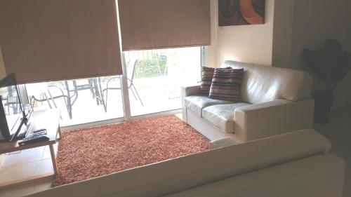 a living room with a couch and a large window at Pyla Gardens A101 in Pyla