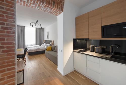 a kitchen with white cabinets and a living room at Aparthotel BC 29 Residence in Kraków