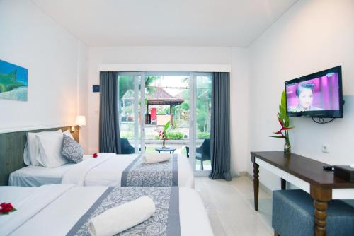 a hotel room with two beds and a flat screen tv at Royal Regantris Villa Karang in Gili Air