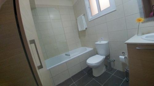 a bathroom with a toilet and a tub and a sink at Pyla Gardens A101 in Pyla