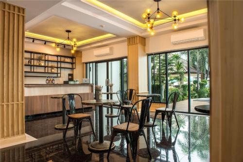 a restaurant with tables and chairs and windows at Golden Foyer Suvarnabhumi Airport Hotel in Lat Krabang