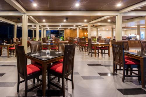 a restaurant with wooden tables and chairs with red seats at Aonang Phu Pi Maan Resort & Spa in Ao Nang Beach