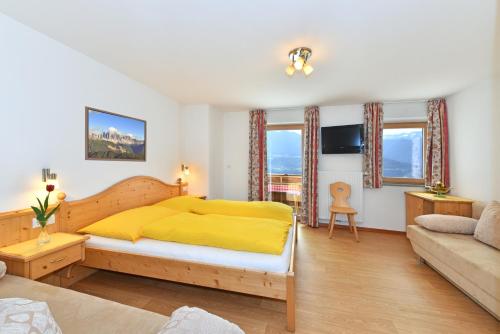1 dormitorio con cama amarilla y sofá en Saderhof, en Brixen