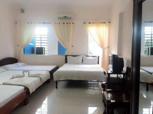 a bedroom with two beds and a tv and windows at Ngoc Phung Guesthouse in Vung Tau
