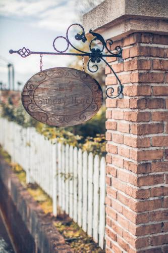 a sign hanging on a brick wall next to a fence at Sunday Home in Dayin