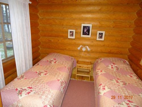 a bedroom with two beds in a log cabin at Matila's Cottages in Sumiainen
