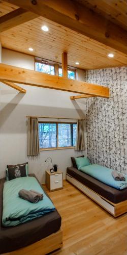 two beds in a room with wooden ceilings at Kitsune Cottages in Hakuba
