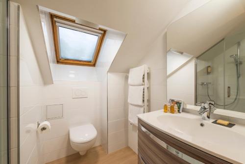 a bathroom with a sink and a toilet and a window at Hotel Eterlou in Méribel