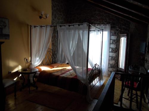 a bedroom with a canopy bed with a window at Theasis suites-Ορεινή Φιλοξενία in Kato Trikala Korinthias