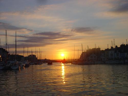 a sunset over a harbor with boats in the water at The Crown Hotel in Weymouth