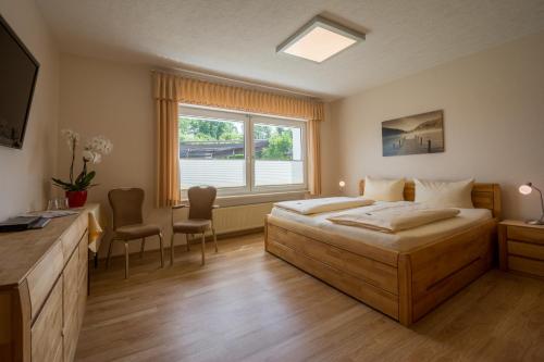 a bedroom with a bed and a desk and a window at Pension Margarethe in Biedenkopf