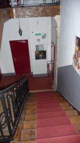 a stairway with a red door and a red carpet at Hôtel du Commerce in Semur-en-Auxois