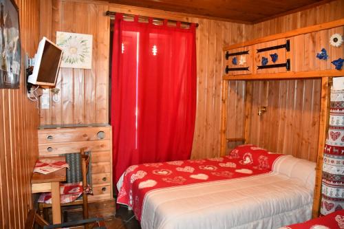 a bedroom with a bed and a red curtain at Hotel Le Terminus in Le Bourg-dʼOisans