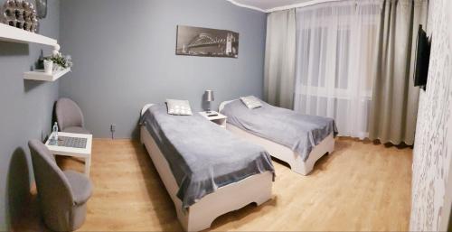 Cette chambre comprend 2 lits et une chaise. dans l'établissement Apartament Silver, à Kielce