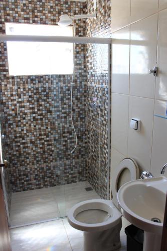 a bathroom with a shower and a toilet and a sink at Pousada Renascer II in Cachoeira Paulista