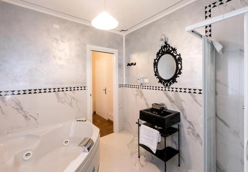 a white bathroom with a tub and a mirror at Il Novecento in Casarsa della Delizia