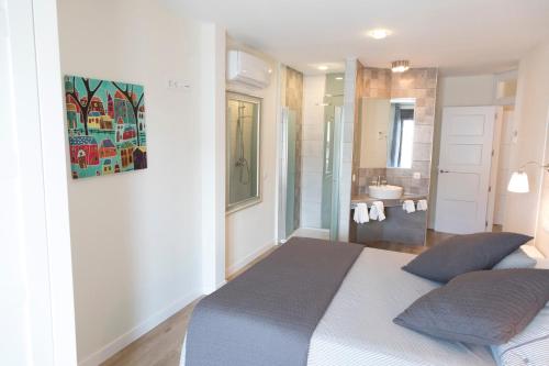 a white bedroom with a bed and a bathroom at Apartamentos Sol Real in Úbeda
